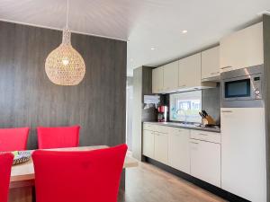 a kitchen with red chairs and a table in a kitchen at Vakantiechalet Serooskerke SE04 in Serooskerke