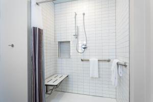 a white tiled bathroom with a bench and a shower at TRYP by Wyndham Orlando in Orlando