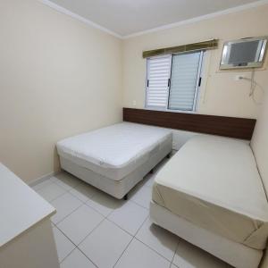 a bedroom with two beds and a tv at APTO UBATUBA-PRAIA GRANDE-CONDOMÍNIO DUBAI in Ubatuba
