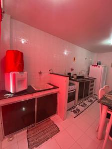 a pink kitchen with a sink and a refrigerator at Residencial Lagomar, sol e mar para relaxar! in Saquarema +17 photos