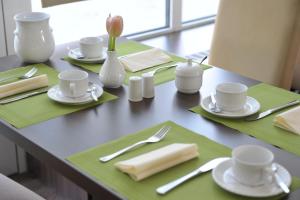 una mesa con manteles verdes, tazas y servilletas en Heikotel - City Nord, en Hamburgo