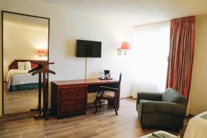 Habitación de hotel con escritorio, cama y espejo en Hotel La Joya Tulancingo, en Tulancingo