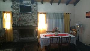 sala de estar con mesa y chimenea de piedra en Finca La Casa Amarilla en San Rafael