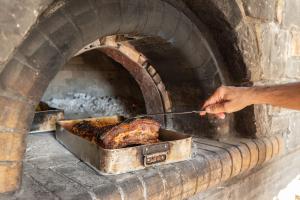a person is cooking a turkey in a brick oven at Mala Villa in Malles