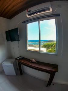 a room with a bench and a window with the ocean at Casa dos Tubarões in Fernando de Noronha