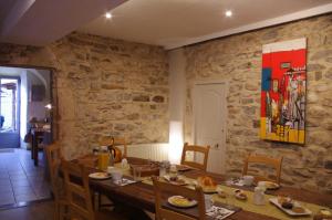a dining room with a table and a stone wall at Le Sareymond in Menée