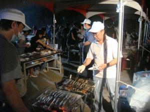 a man cooking food on a grill in a market at Mini Home B&B in Kangle