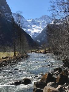a river with snow capped mountains in the background at Hornerpub Apartments in Lauterbrunnen