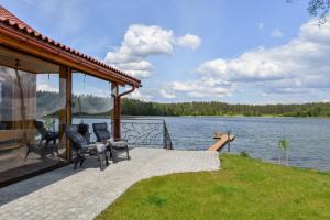 a pavilion with chairs on the side of a lake at Vila LATO, Druskininkai in Latežeris