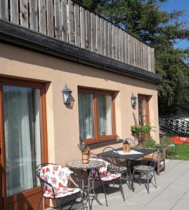 patio ze stołami i krzesłami oraz ogrodzeniem w obiekcie Gartenwohnung auf der Sommeralm w mieście Sankt Kathrein am Offenegg