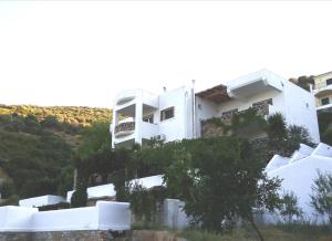 biały budynek na szczycie wzgórza w obiekcie Erifili Homes w mieście Áyioi Apóstoloi