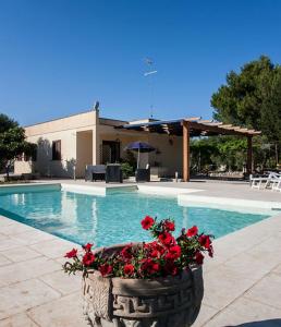 una piscina con un vaso con fiori rossi di Villa con piscina vicino Otranto a Carpignano Salentino