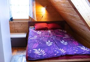 a bed with a purple comforter in a wooden room at Mesikamäe Saunamaja in Põlva