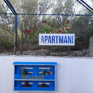 a sign on a wall with a blue window at Apartmani Ola in Drače