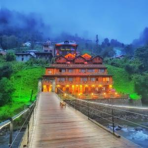 a large building on a bridge over a river at Nani Boutique Hotel & Bungalow in Çamlıhemşin