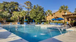 einen Pool mit einem Brunnen mit Stühlen und Sonnenschirmen in der Unterkunft Spinnaker at Shipyard in Hilton Head Island