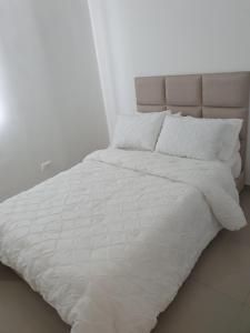 un letto bianco con lenzuola e cuscini bianchi di Excelente Apartamento Completo, en la mejor zona a Cúcuta