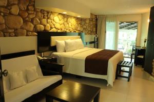 Habitación de hotel con cama y sofá en Hotel Nututun Palenque en Palenque
