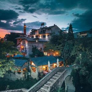 ein Gebäude auf einem Hügel mit einer Brücke davor in der Unterkunft Hotel-Restaurant Kriva Ćuprija in Mostar