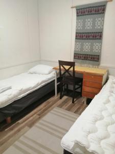 a room with two beds and a desk and a chair at Köpsintie 4 B in Pyhäsalmi