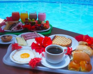 una bandeja de desayuno en una mesa junto a la piscina en Pousada Recanto dos Corais en Porto de Galinhas