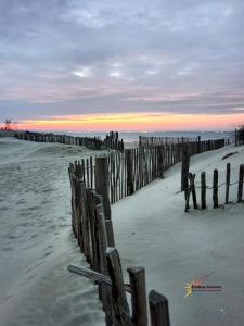 a beach with a wooden fence in the sand at Studio 237 Port Camargue, Piscine, Climatisation, 2 personnes in Le Grau-du-Roi