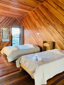 three beds in a room with wooden walls at Cabinas Selva Verde in Monteverde Costa Rica