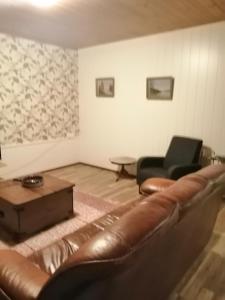 a living room with a leather couch and a chair at Köpsintie 4 B in Pyhäsalmi