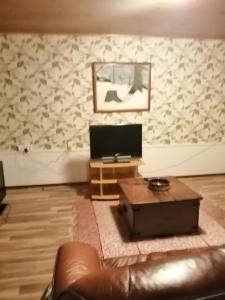 a living room with a leather couch and a television at Köpsintie 4 B in Pyhäsalmi