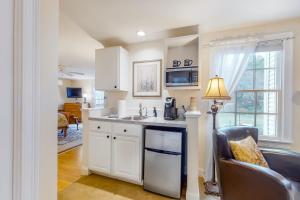 a kitchen with white cabinets and a sink and a chair at Brewster by the Sea Inn in Brewster