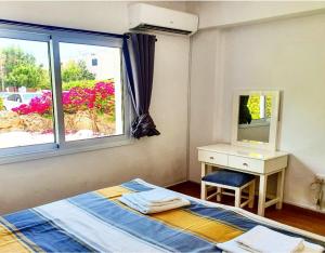 een slaapkamer met een bed, een bureau en een raam bij Prima Casa 005 in Paphos City