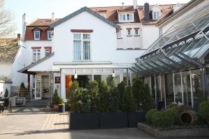 a white house with a glass greenhouse in front of it at Hotel Goldener Stern in Sankt Ingbert