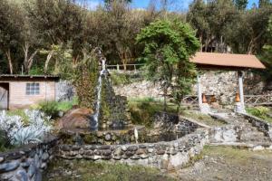 uma fonte num jardim com uma parede de pedra em Hostería Cabañas del Pescador em Cajas