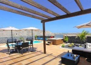 un patio avec une table, des chaises et un parasol dans l'établissement Villa Emma Playa Blanca, à Playa Blanca 30 autres photos