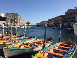 four boats are docked in a canal with buildings at Amarine joli T3 Centre Ville terrasse parking et vélos in Sète