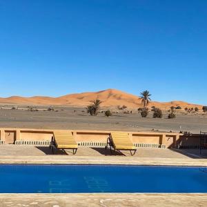 two chairs and a swimming pool in the desert at Dar Marhaba Merzouga in Merzouga