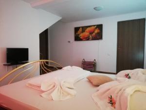 a bedroom with a bed with white sheets and a tv at Horia in Avrig