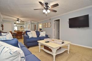 a living room with a blue couch and a tv at Direct Beachfront Delight by Beachside Management in Siesta Key