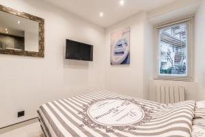 a white bedroom with a bed and a tv at Lac et Montagne in Veyrier-du-Lac