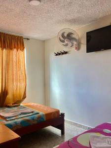 a bedroom with a bed and a tv on the wall at Hotel Mansión Real in Bucaramanga