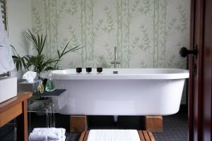 アビンドン・オン・テムズにあるB&B Raftersの緑の壁紙を使用したバスルーム(白いバスタブ付)