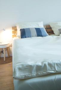 Una cama blanca con sábanas azules y blancas y una mesa. en Q55 - Quartier 55 en Quickborn