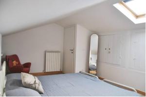 a white bedroom with a bed and a chair at Civico 5 in Assisi