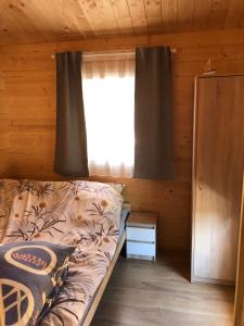a bed in a wooden room with a window at WAKACYJNE ZAGAJE in Sarbinowo