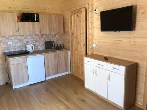 a kitchen with white cabinets and a flat screen tv at WAKACYJNE ZAGAJE in Sarbinowo +9 photos