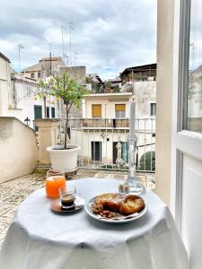 La Residenza del Reginale في سيراكوزا: طاولة مع طبق من الطعام وعصير البرتقال