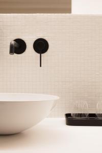 a bathroom with a white tiled wall with a sink at Vertes Feuilles in Saint-Sauveur