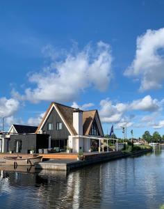 a house on a dock next to a body of water at New high end waterfront family villa in Stavoren