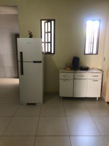 uma cozinha com um frigorífico branco num quarto em De Angelis - Casa de praia em Piuma com WI-FI em Piúma