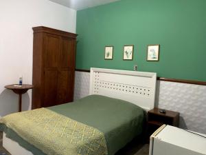 1 dormitorio con cama y pared verde en Pousada Manga Rosa en São João Batista do Glória